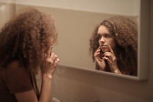 Woman looking in the mirror concerned with stressed out skin